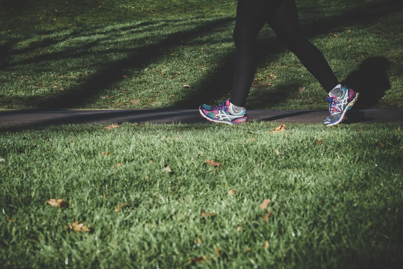 A person in running shoes walking along a green path